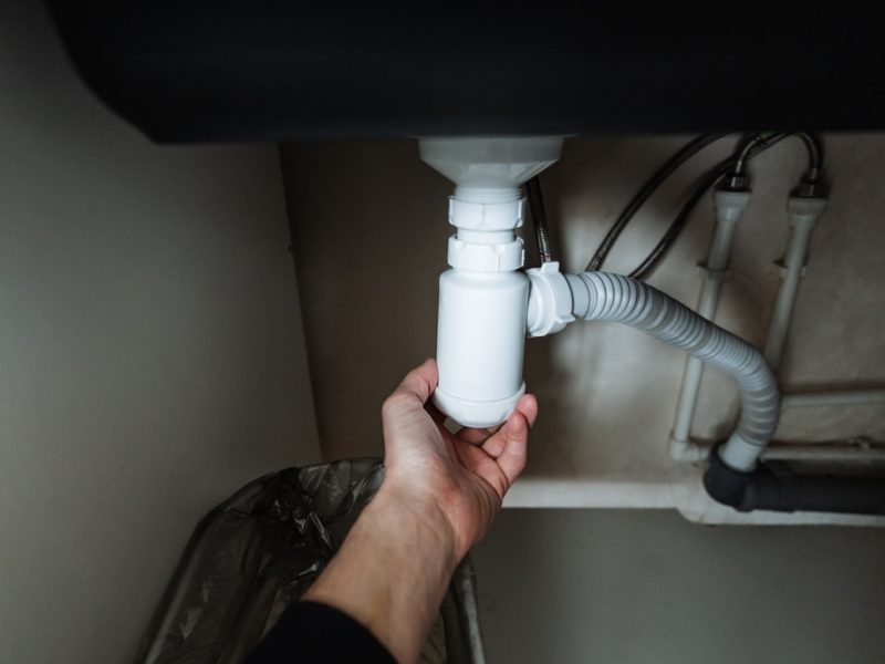 A,Person,Is,Carefully,Holding,A,Drain,Pipe,Positioned,Underneath