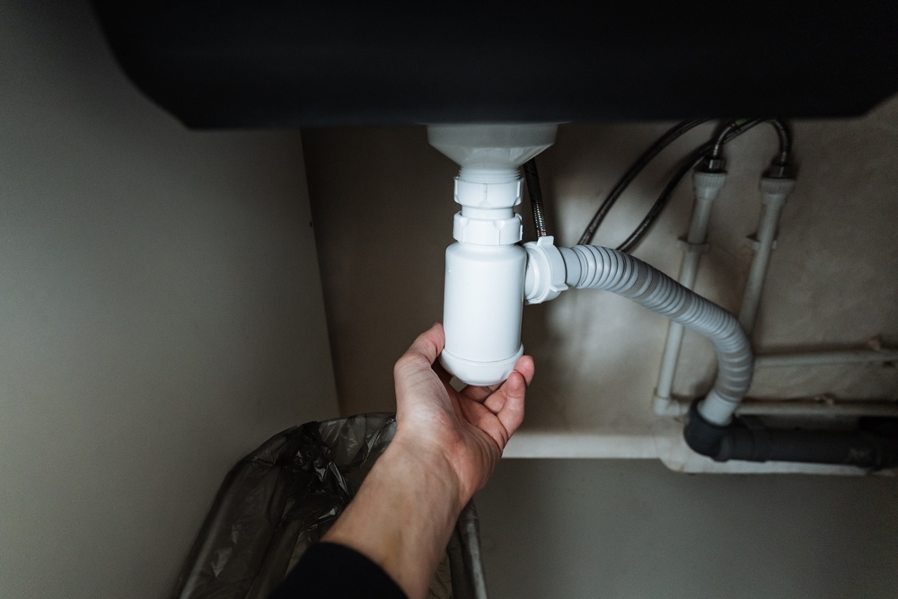 A,Person,Is,Carefully,Holding,A,Drain,Pipe,Positioned,Underneath