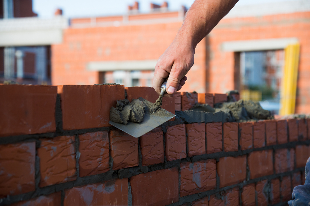 Bricklayer,Worker,Installing,Brick,Masonry,On,Exterior,Wall.,Professional,Construction